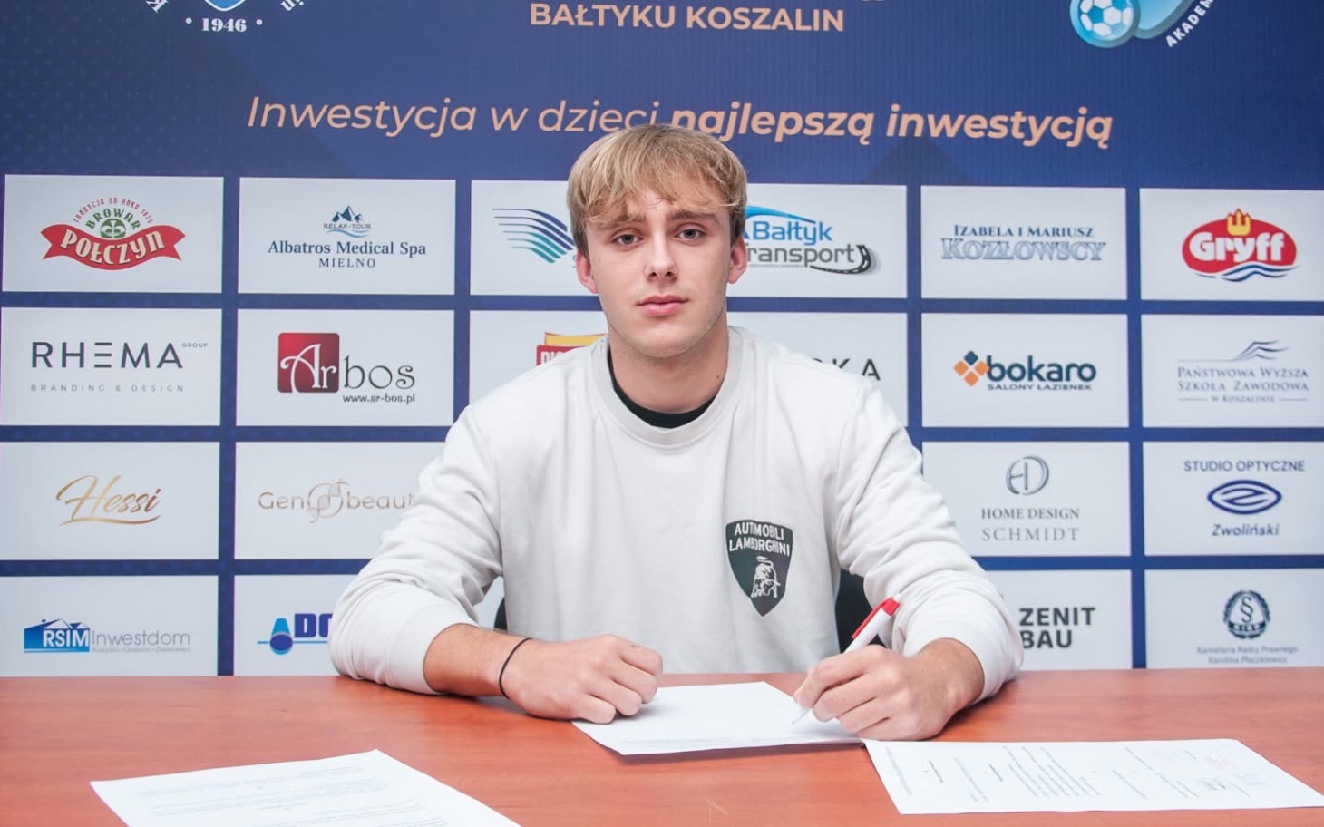 
        Młody mężczyzna podpisujący dokumenty w biurze.
    