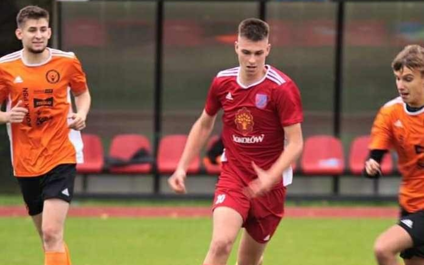 
        Młodzi piłkarze w akcji na boisku, pełni energii.
    