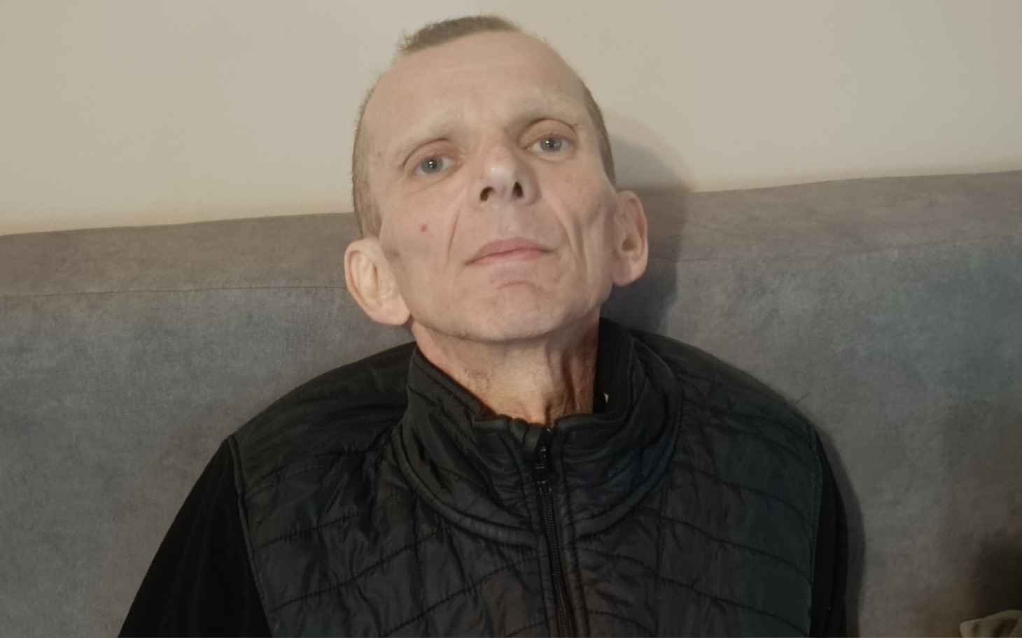 
        Mężczyzna z chudą sylwetką, siedzący na kanapie.
    