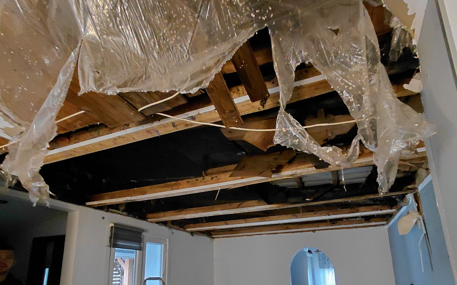 
        Uszkodzony sufit w pomieszczeniu, widoczne drewniane belki.
    