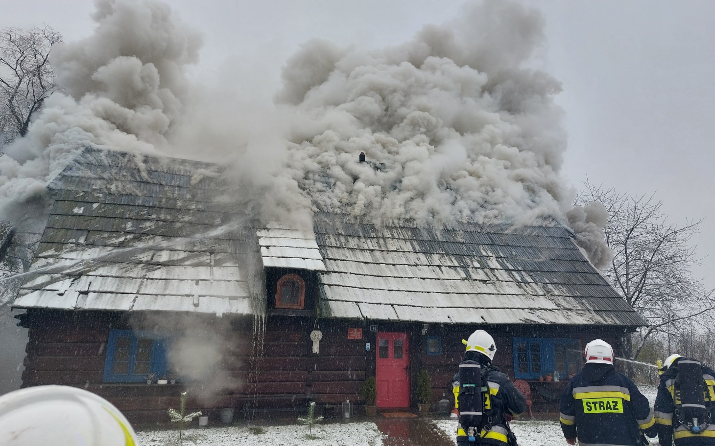 
        Dym wydobywający się z płonącego drewnianego domu.
    