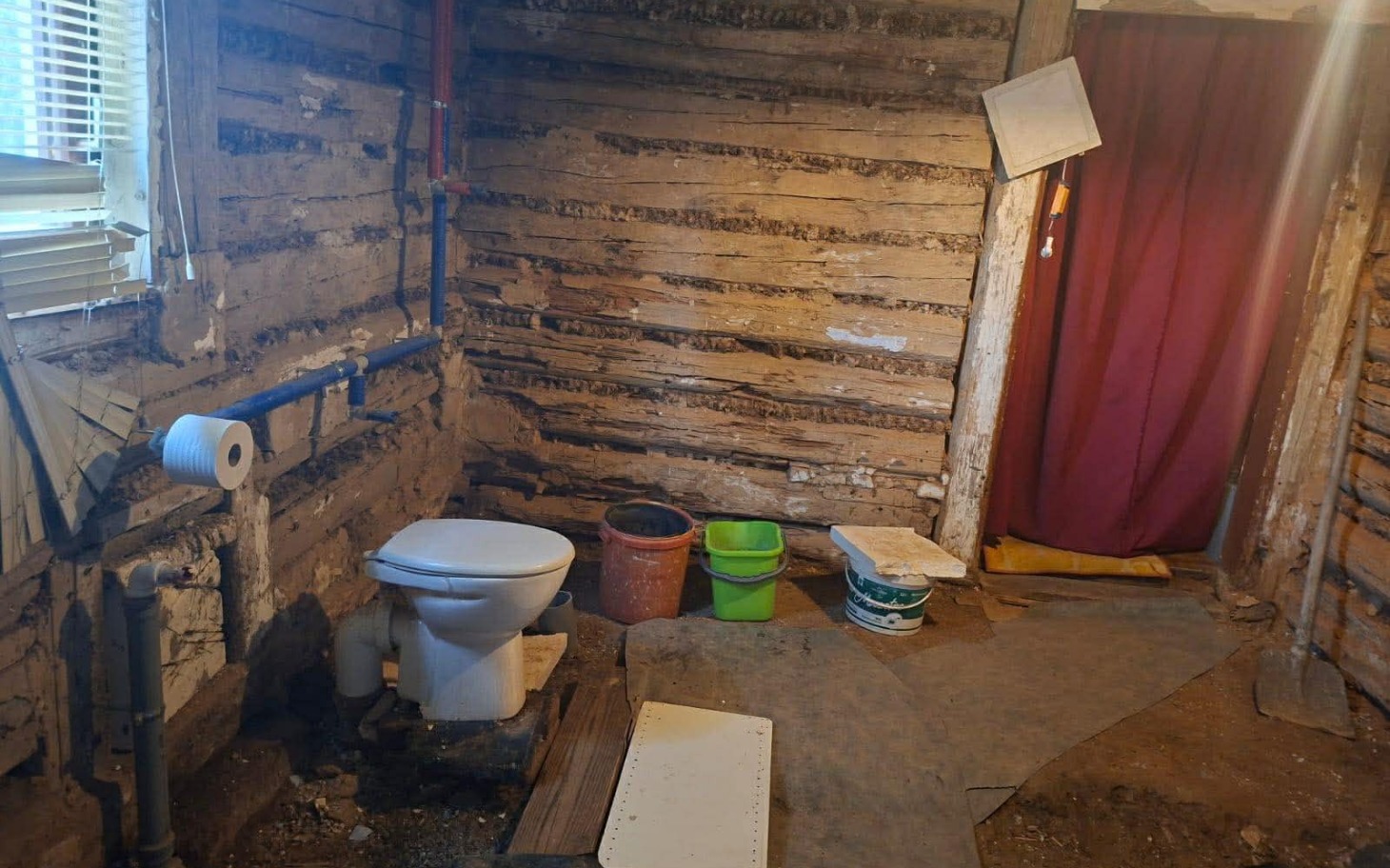 
        Wnętrze starej chaty z toaletą i zasłoną.
    