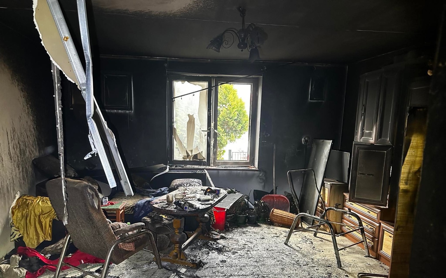 
        Zniszczony pokój po pożarze, z popiołem i zniszczeniami.
    