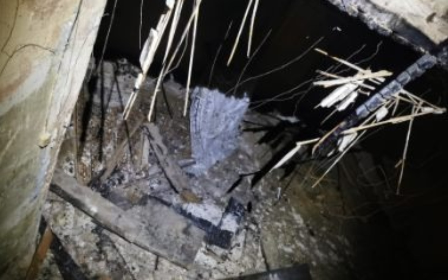 
        Zniszczone wnętrze budynku po pożarze, z resztkami materiałów budowlanych.
    