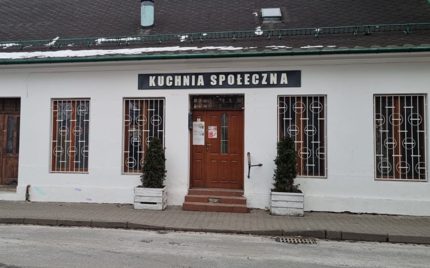 
        Budynek z napisem 'Kuchnia Społeczna', miejsce wsparcia dla potrzebujących.
    