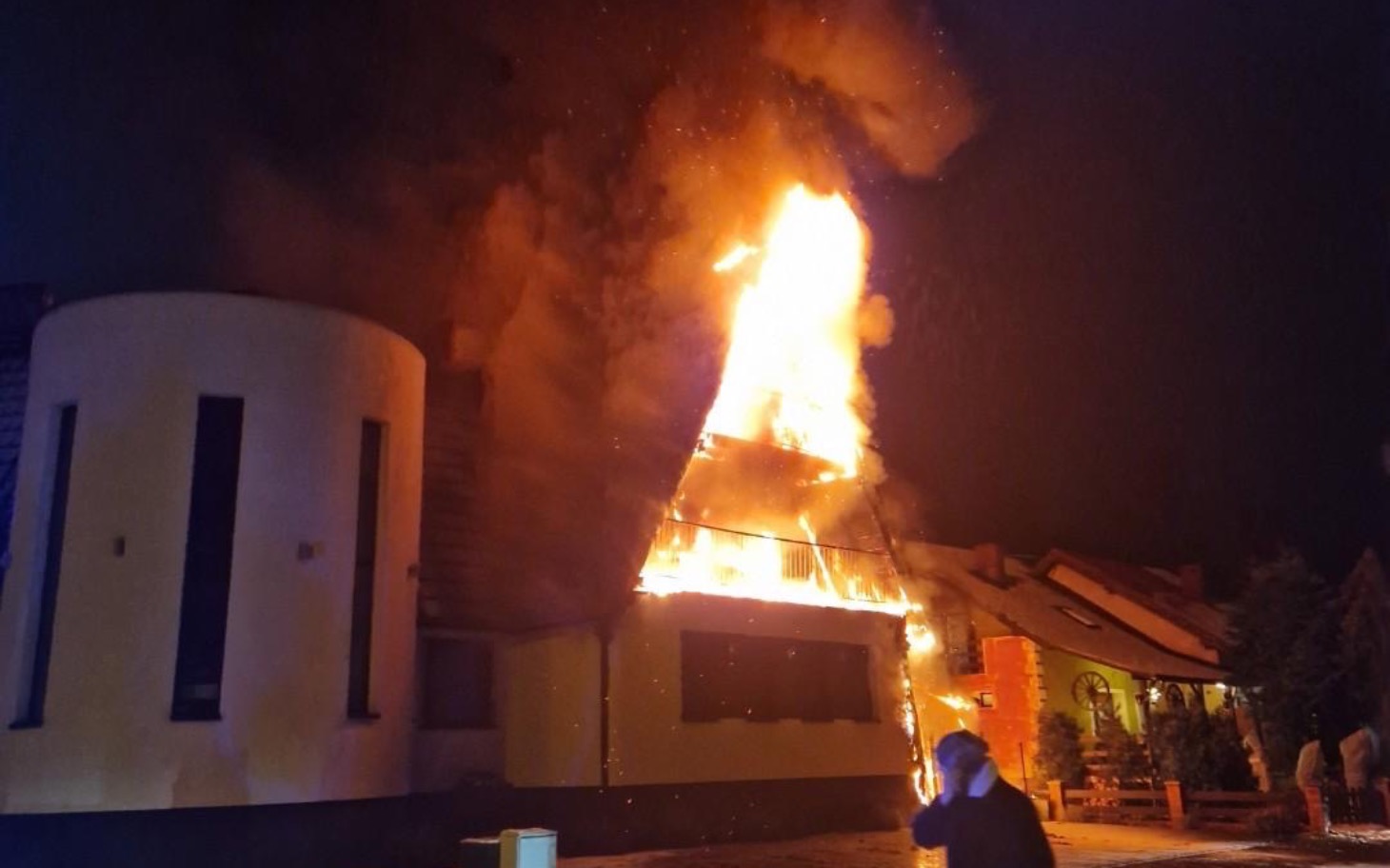 
        Pożar w budynku, ogień wydobywający się z dachu.
    