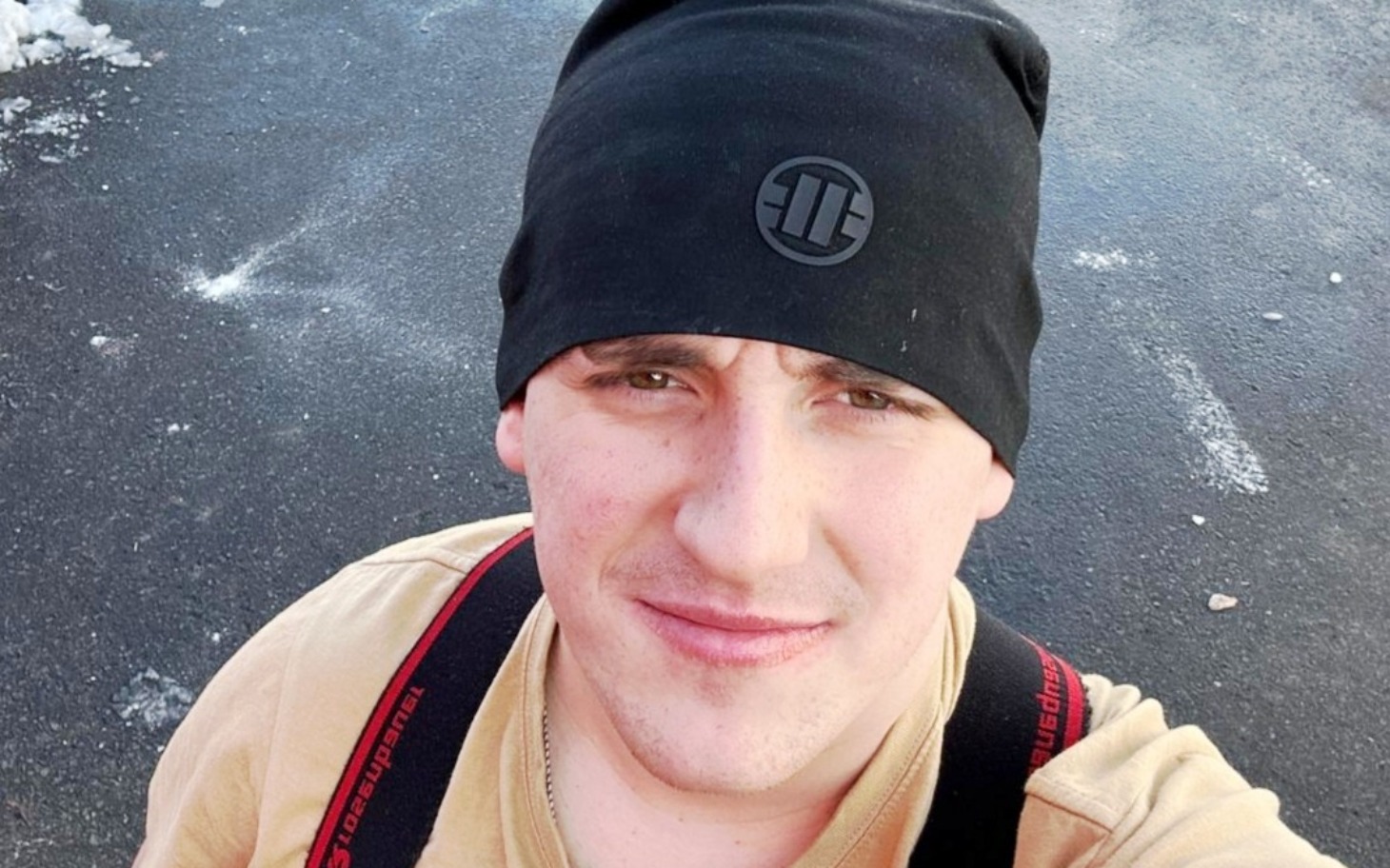 
        Mężczyzna w czapce na tle asfaltu.
    