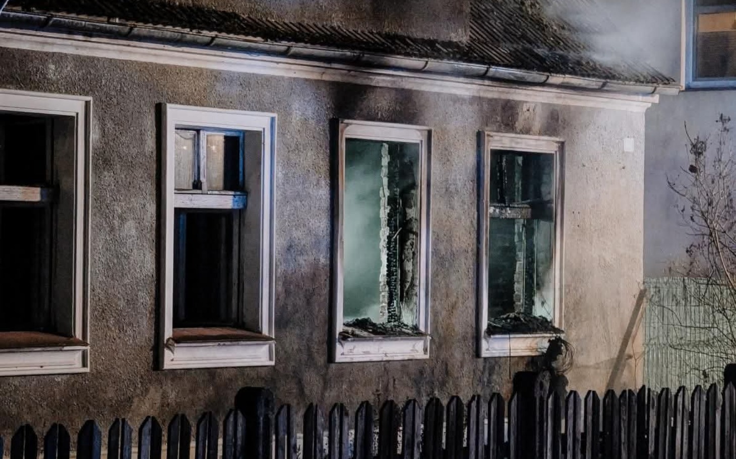 
        Zniszczony dom po pożarze, z oknami bez szyb.
    