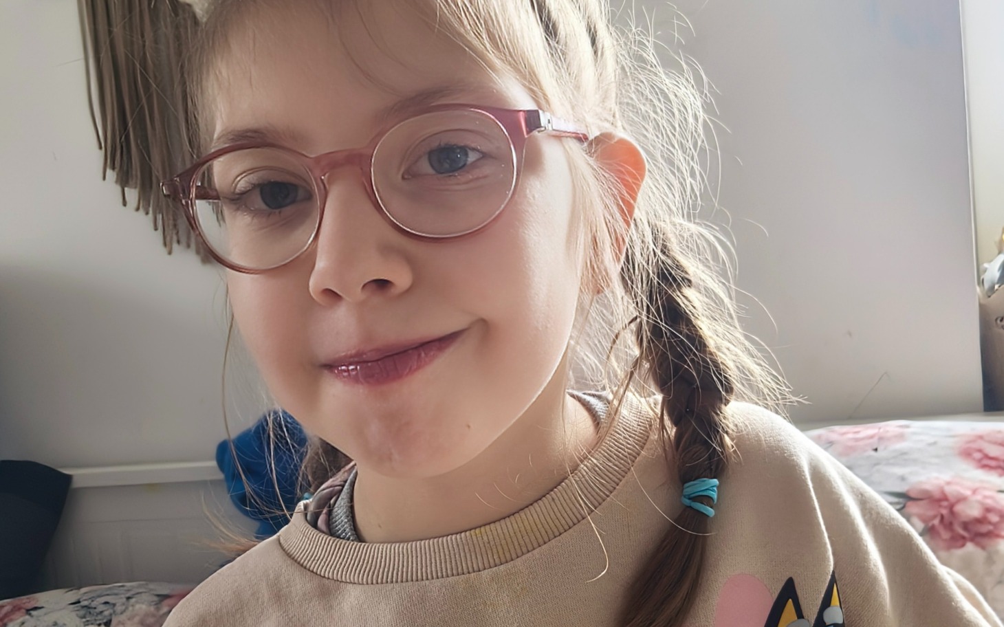 
        Uśmiechnięta dziewczynka w okularach, pozująca do zdjęcia.
    