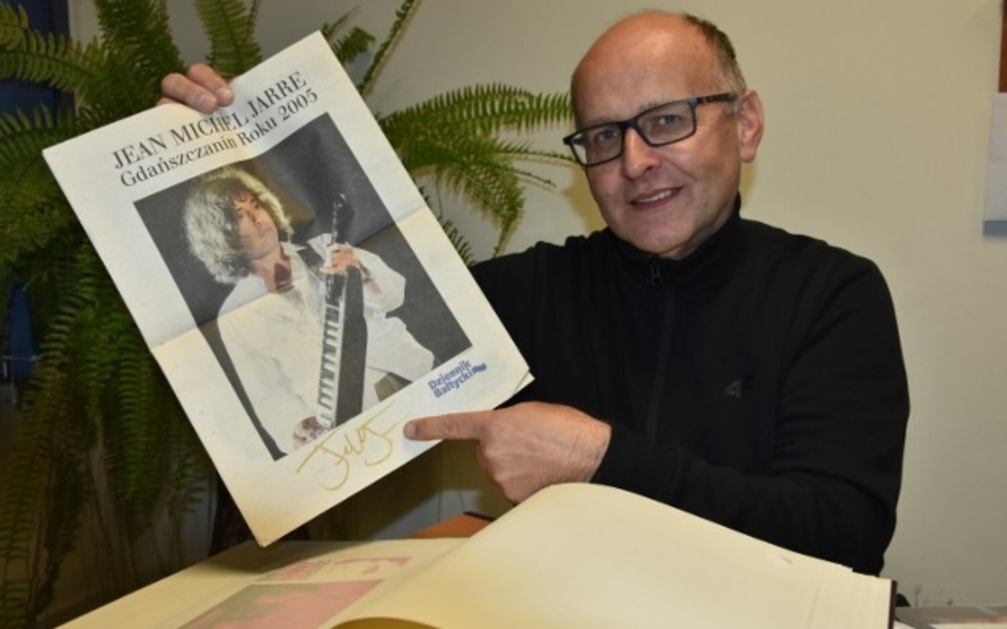 
        Mężczyzna trzyma plakat Jean-Michel Jarre'a z autografem.
    