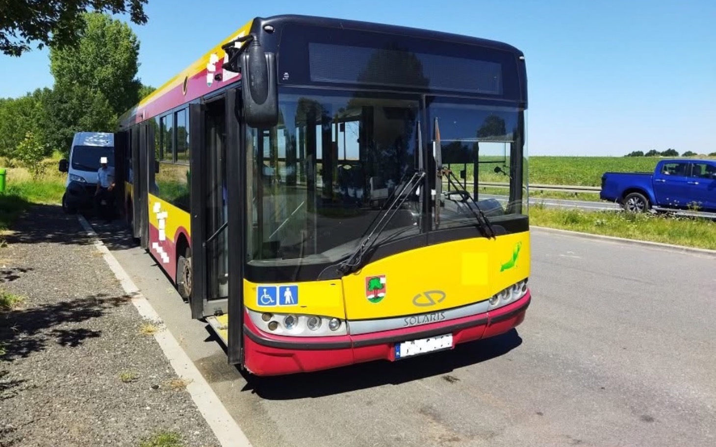 
        Autobus stojący na poboczu drogi w zielonym otoczeniu.
    