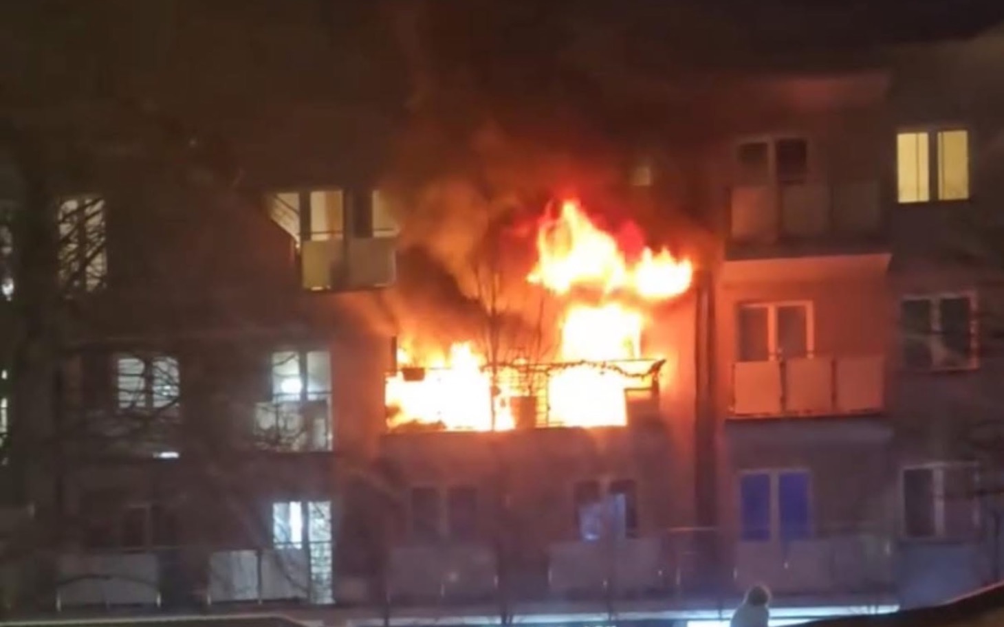 
        Pożar na balkonie budynku mieszkalnego w nocy.
    