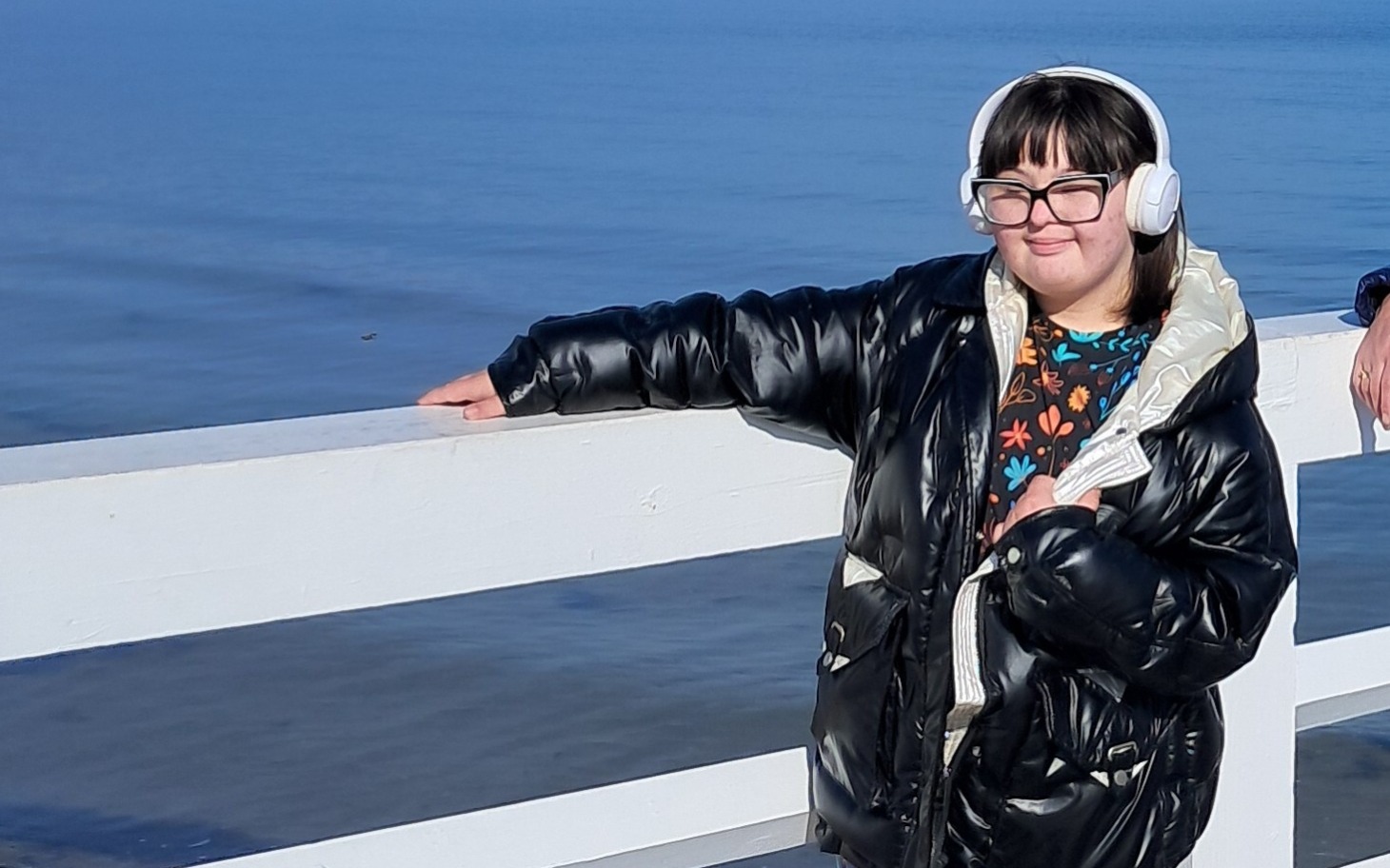 
        Dziewczynka w słuchawkach na tle morza.
    