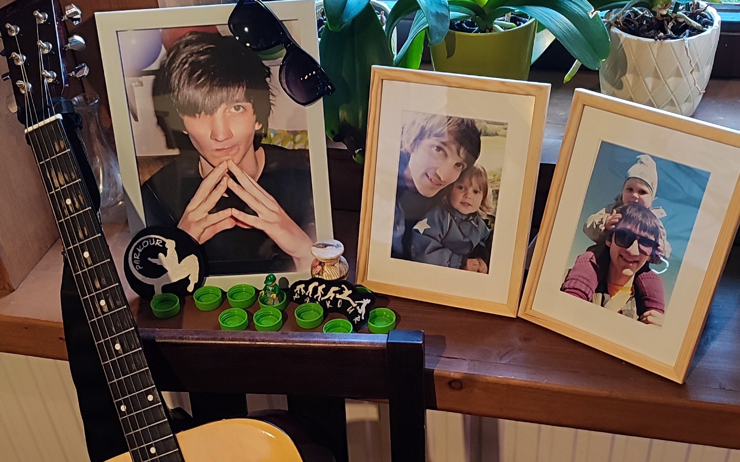 
        Rodzinne zdjęcia na stole z gitarą i roślinami.
    