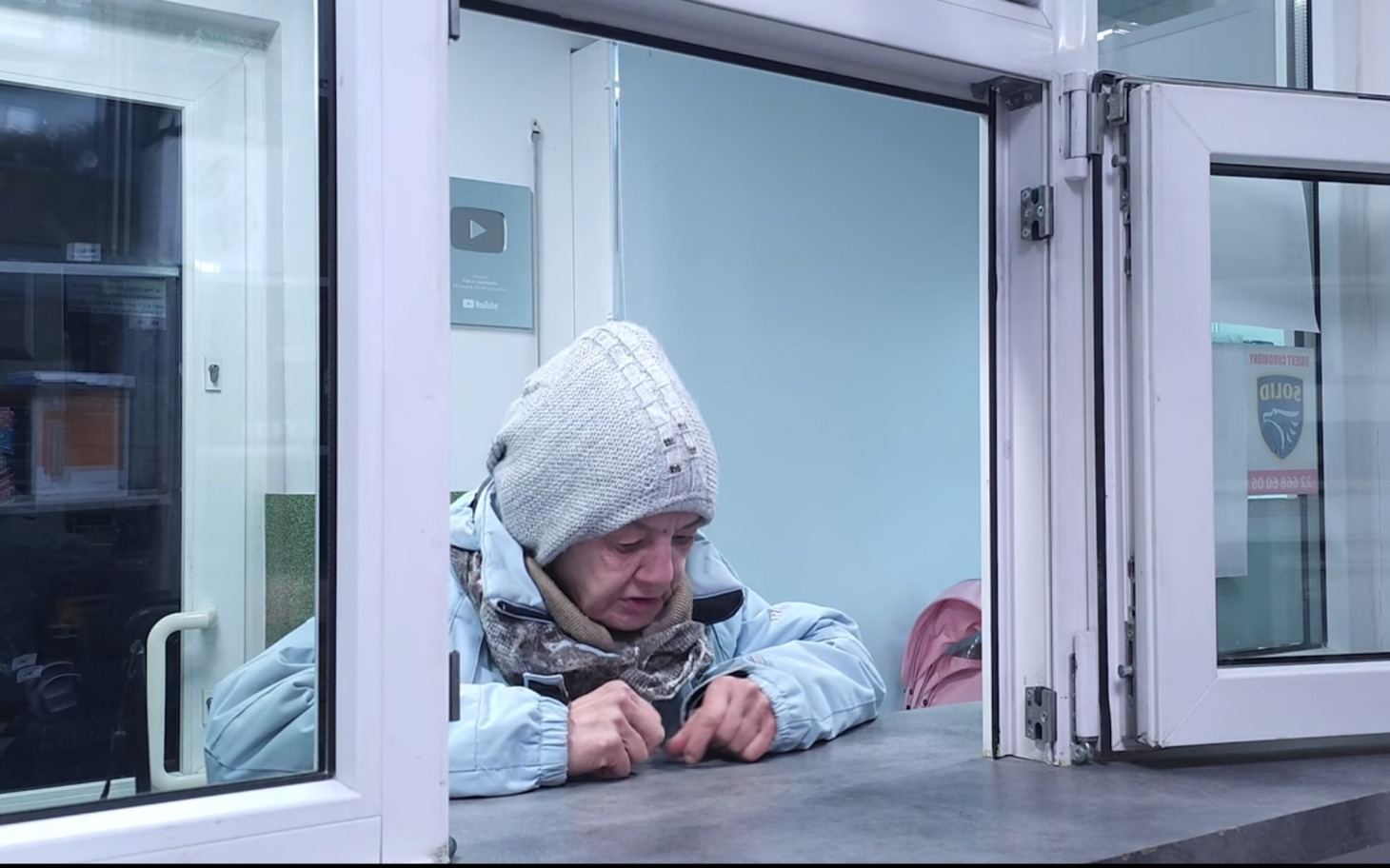 
        Kobieta w czapce, siedząca przy oknie.
    