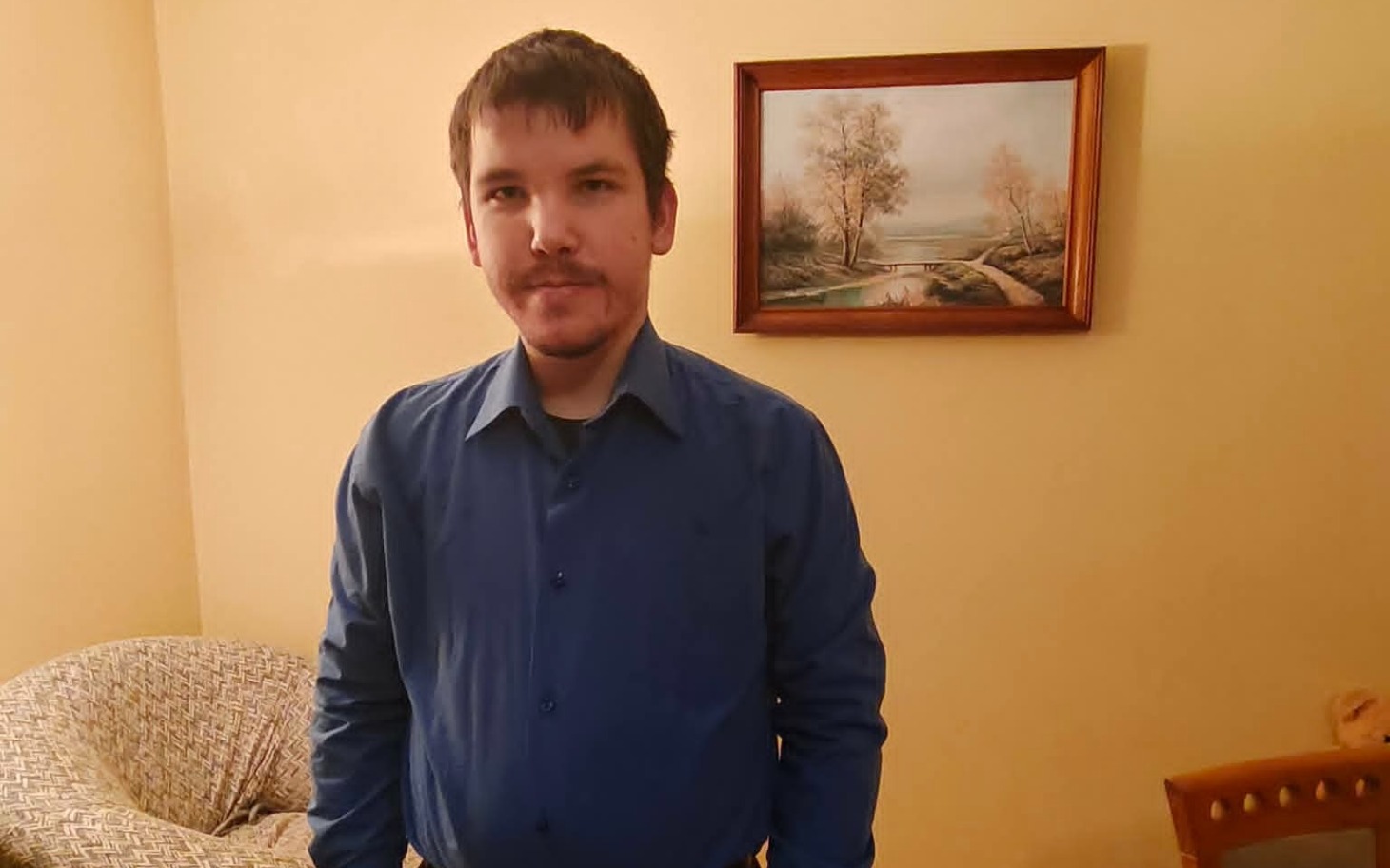 
        Mężczyzna w niebieskiej koszuli w domowym otoczeniu.
    