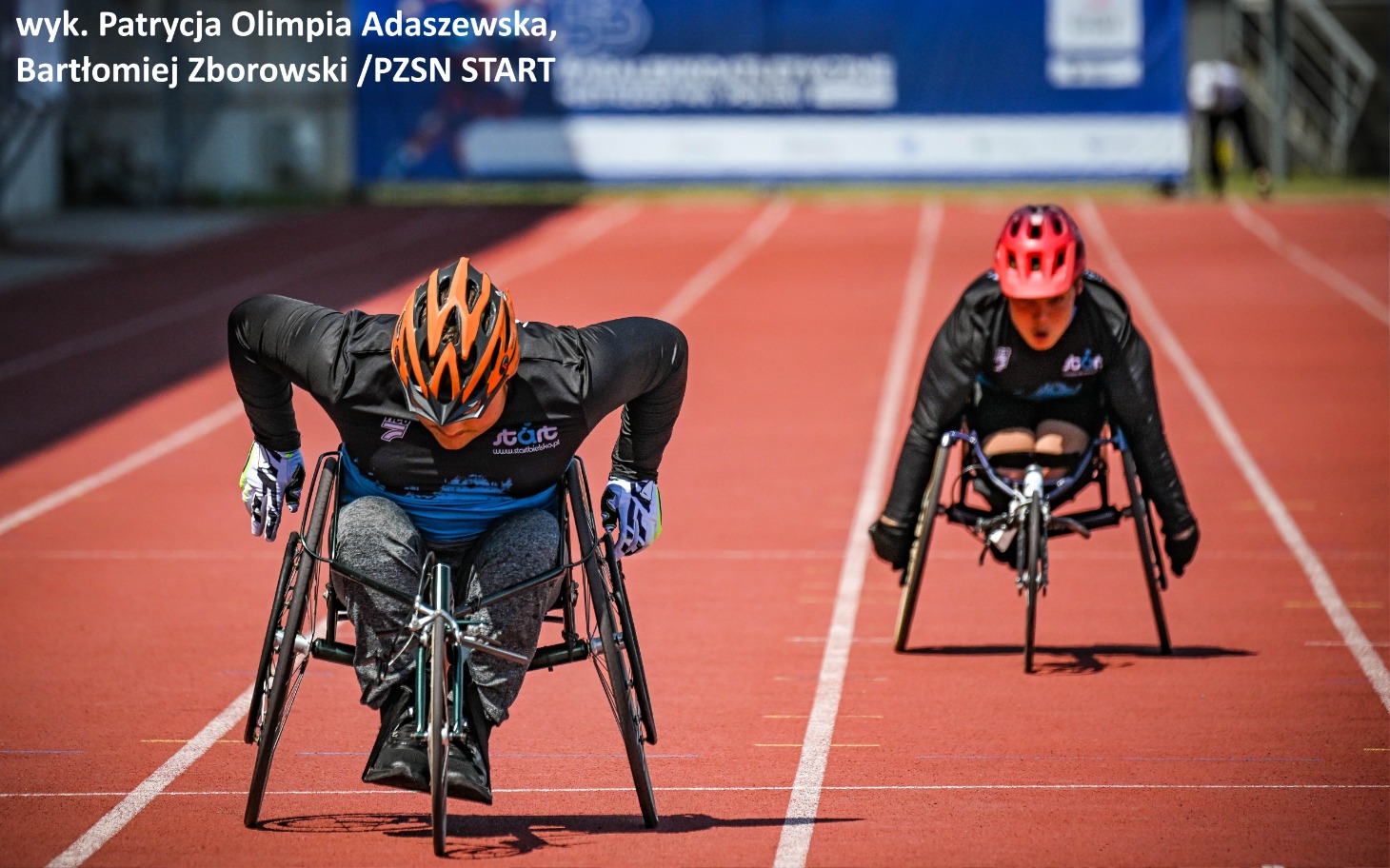 
        Zawodnicy na wózkach inwalidzkich rywalizujący na torze lekkoatletycznym.
    