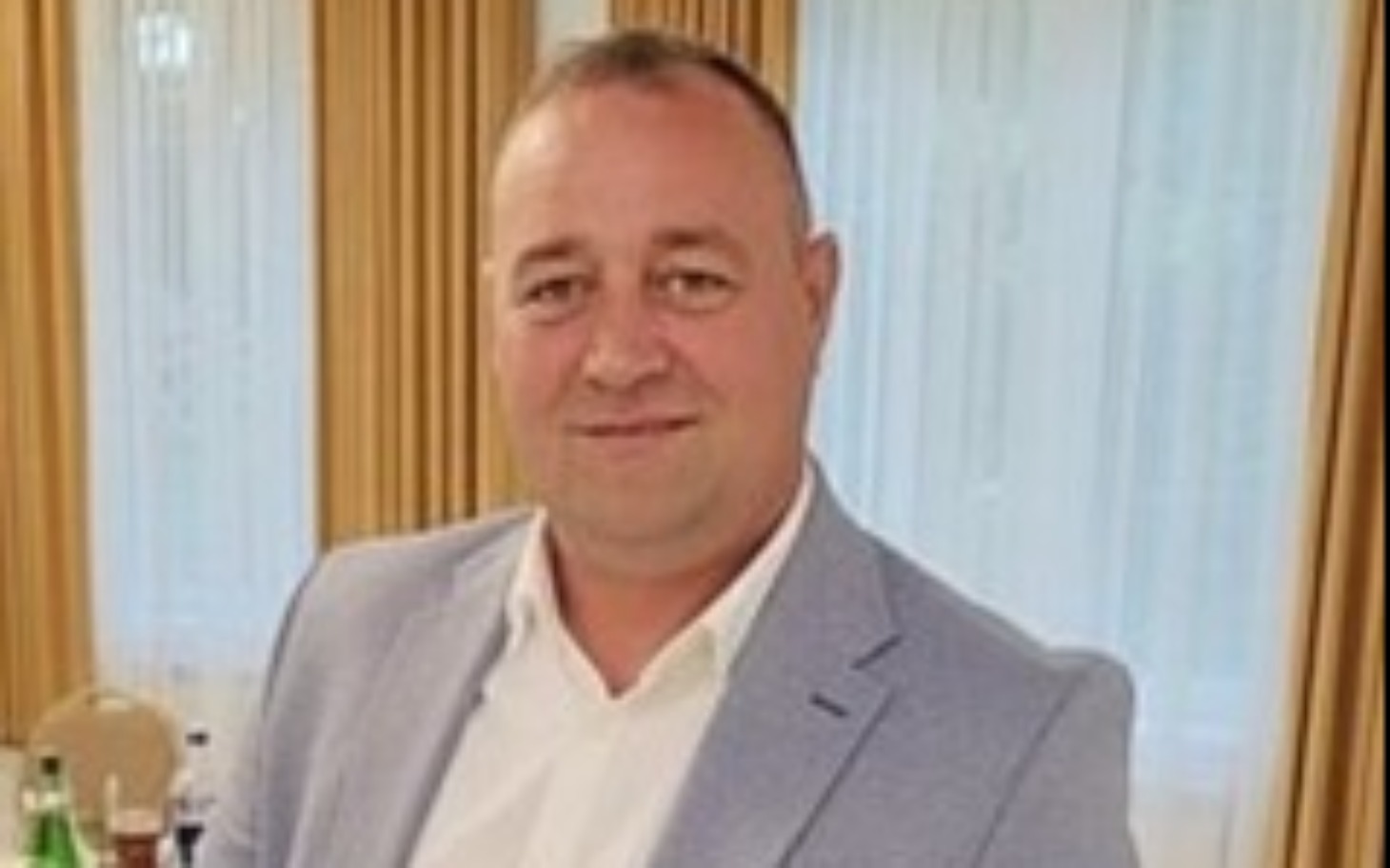 
        Mężczyzna w garniturze, uśmiechający się do kamery.
    