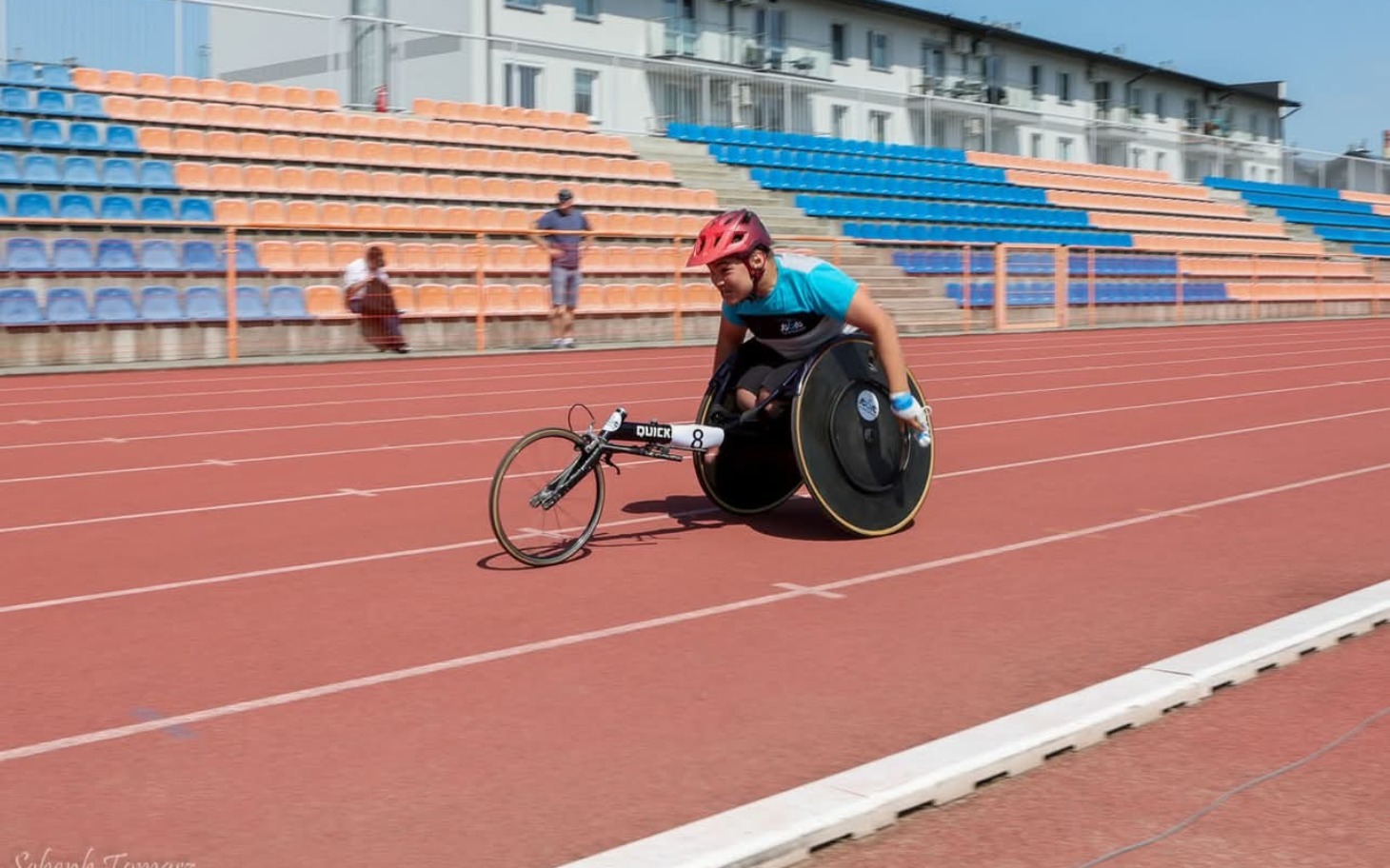 
        Sportowiec na wózku inwalidzkim na bieżni, pełen determinacji.
    