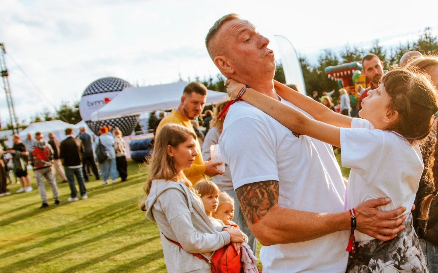 Mężczyzna bawi się z dzieckiem na festiwalu, radosna atmosfera.