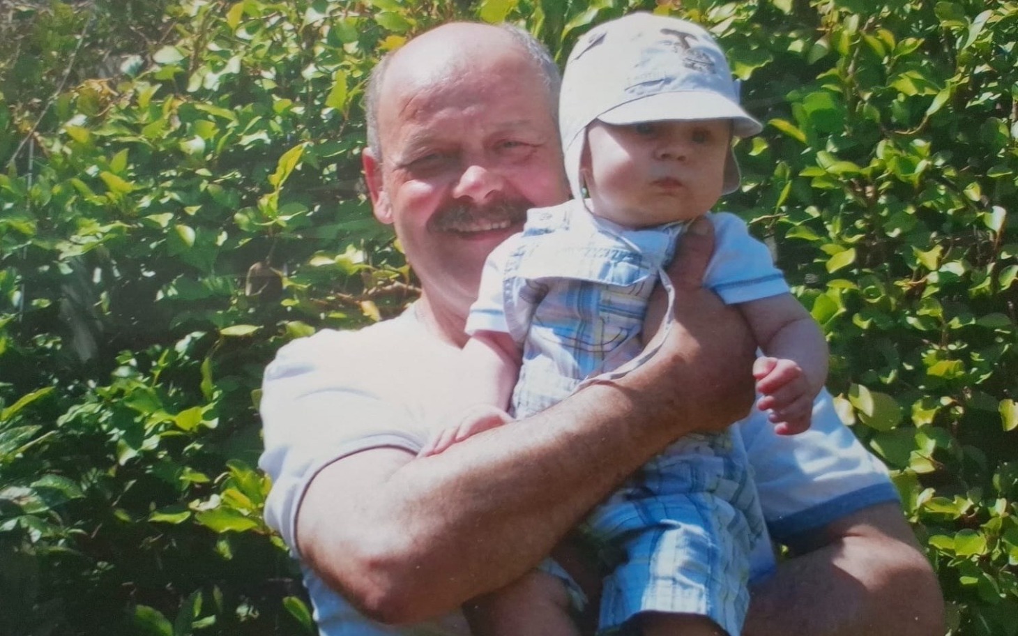 
        Mężczyzna trzymający małe dziecko w kapeluszu.
    