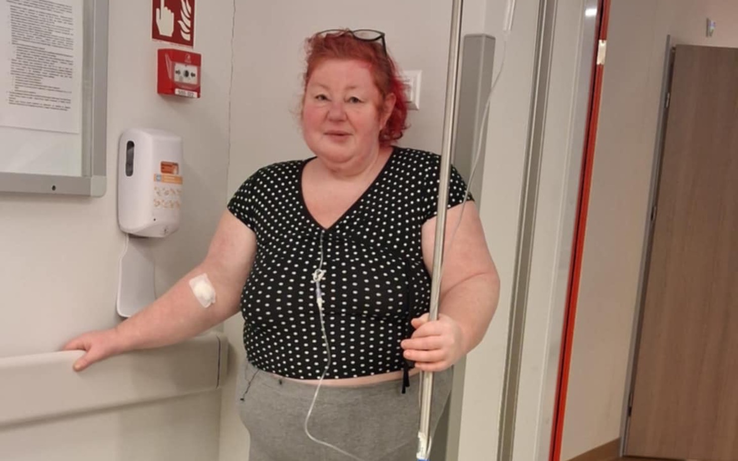 
        Kobieta w szpitalu, z uśmiechem i kroplówką.
    