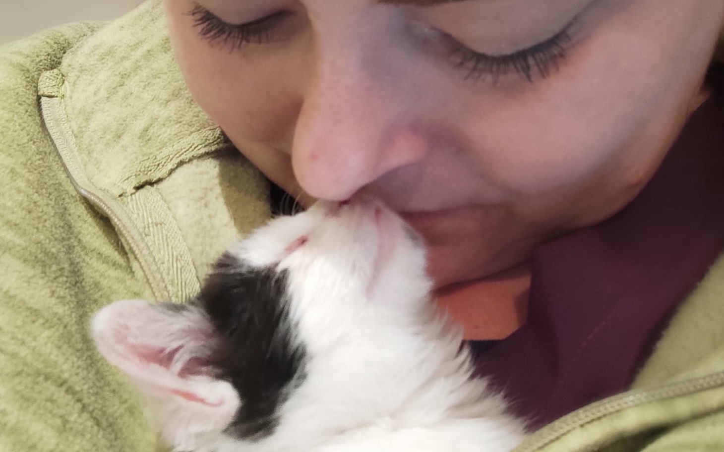 
        Kobieta przytula małego kota, dzieląc się czułym momentem.
    