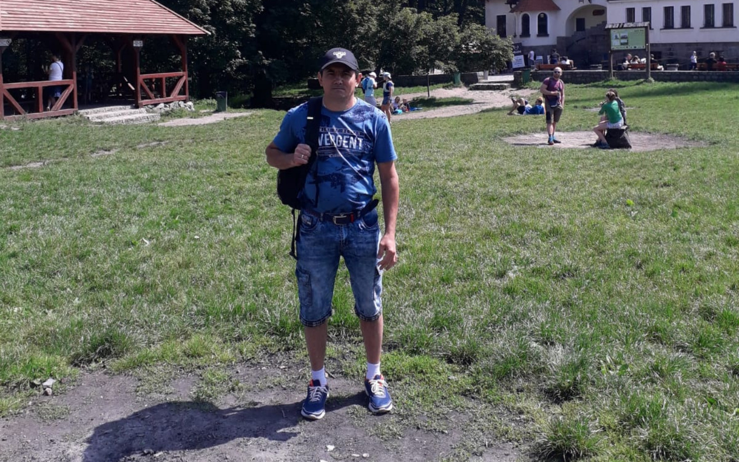 
        Mężczyzna w niebieskiej koszulce na tle zielonej trawy.
    