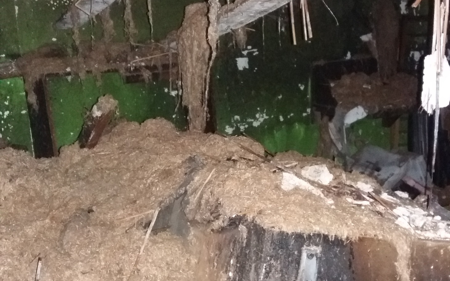 
        Zniszczone wnętrze z dużą ilością siana.
    