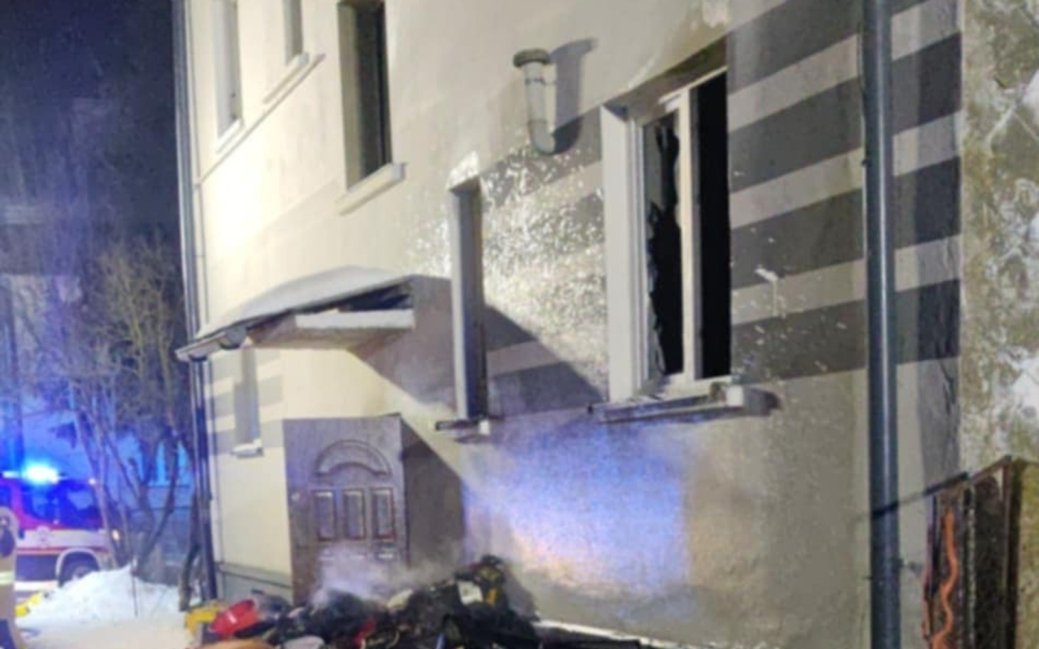 
        Zniszczony budynek po pożarze, z dymem i uszkodzonymi oknami.
    