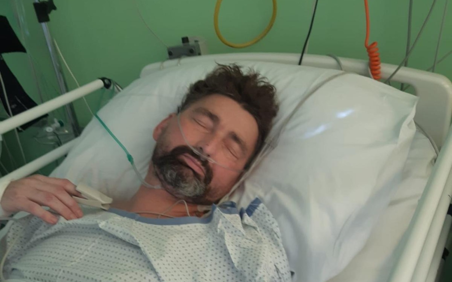 
        Mężczyzna w szpitalnym łóżku, z zamkniętymi oczami.
    