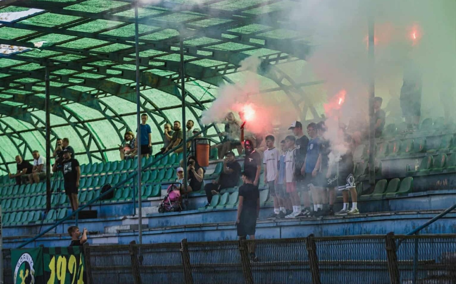 
        Fani na stadionie z racami, tworzący atmosferę wsparcia.
    