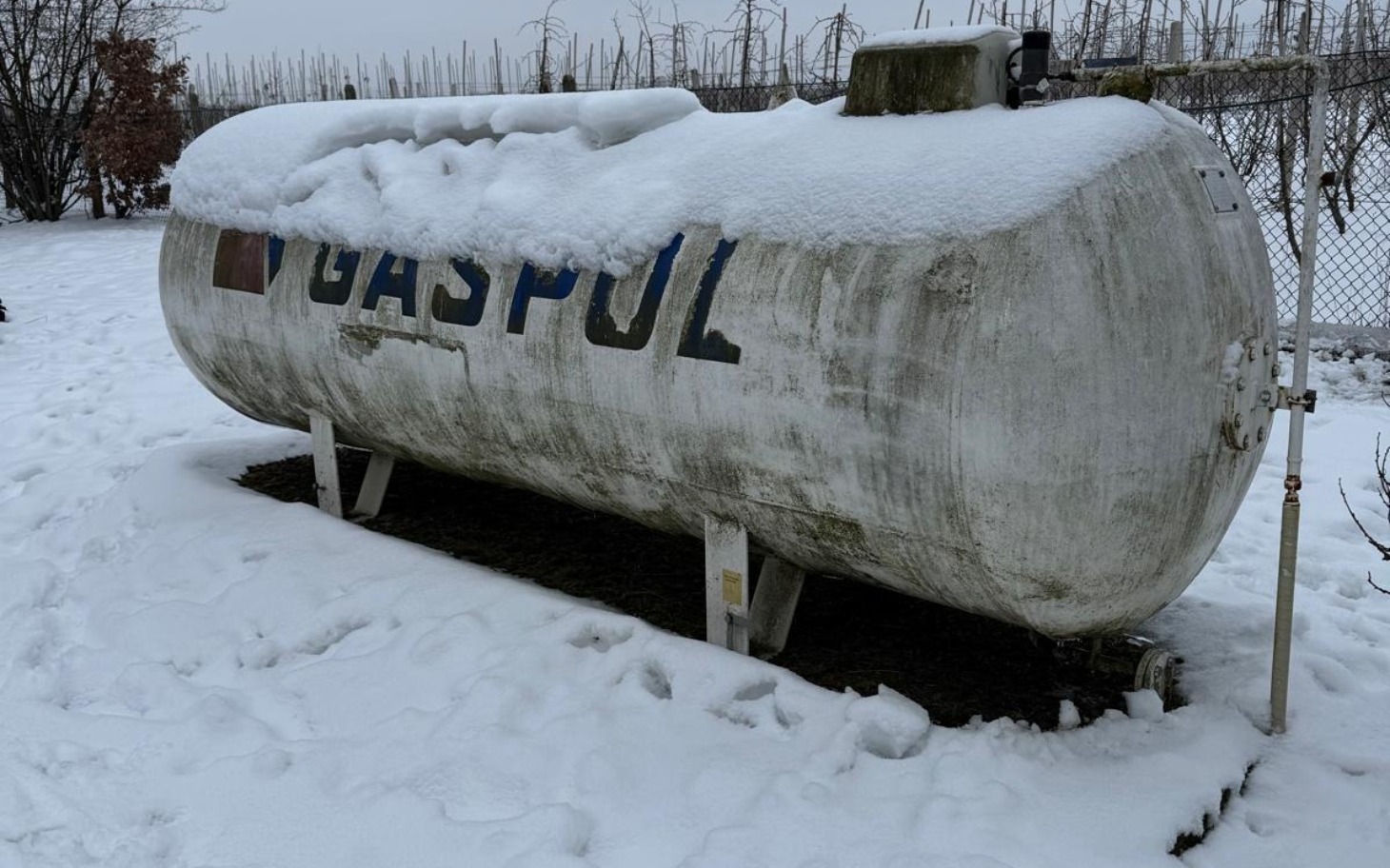 
        Zbiornik gazowy pokryty śniegiem, w zimowym otoczeniu.
    