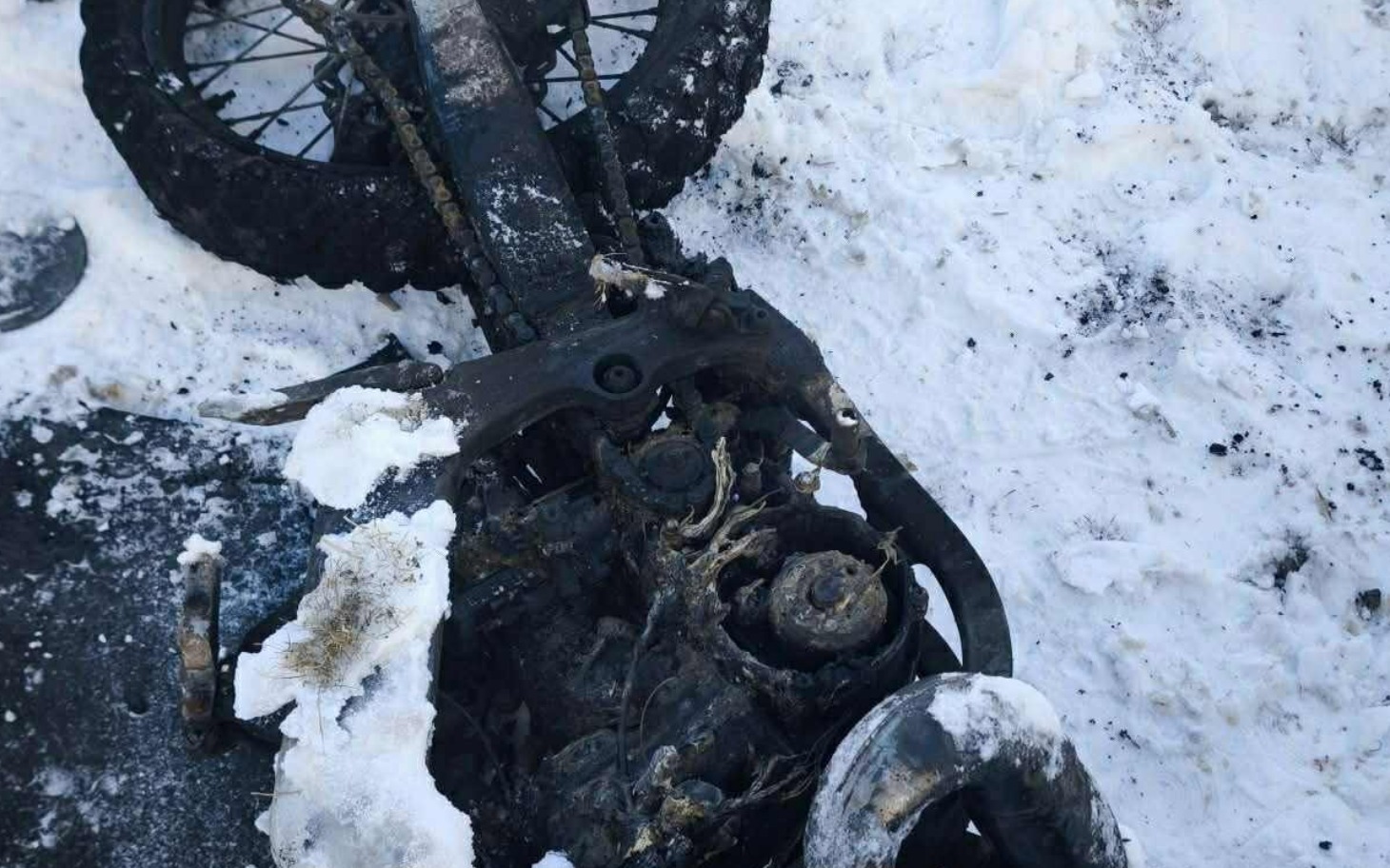 
        Zniszczony motocykl leżący w śniegu.
    