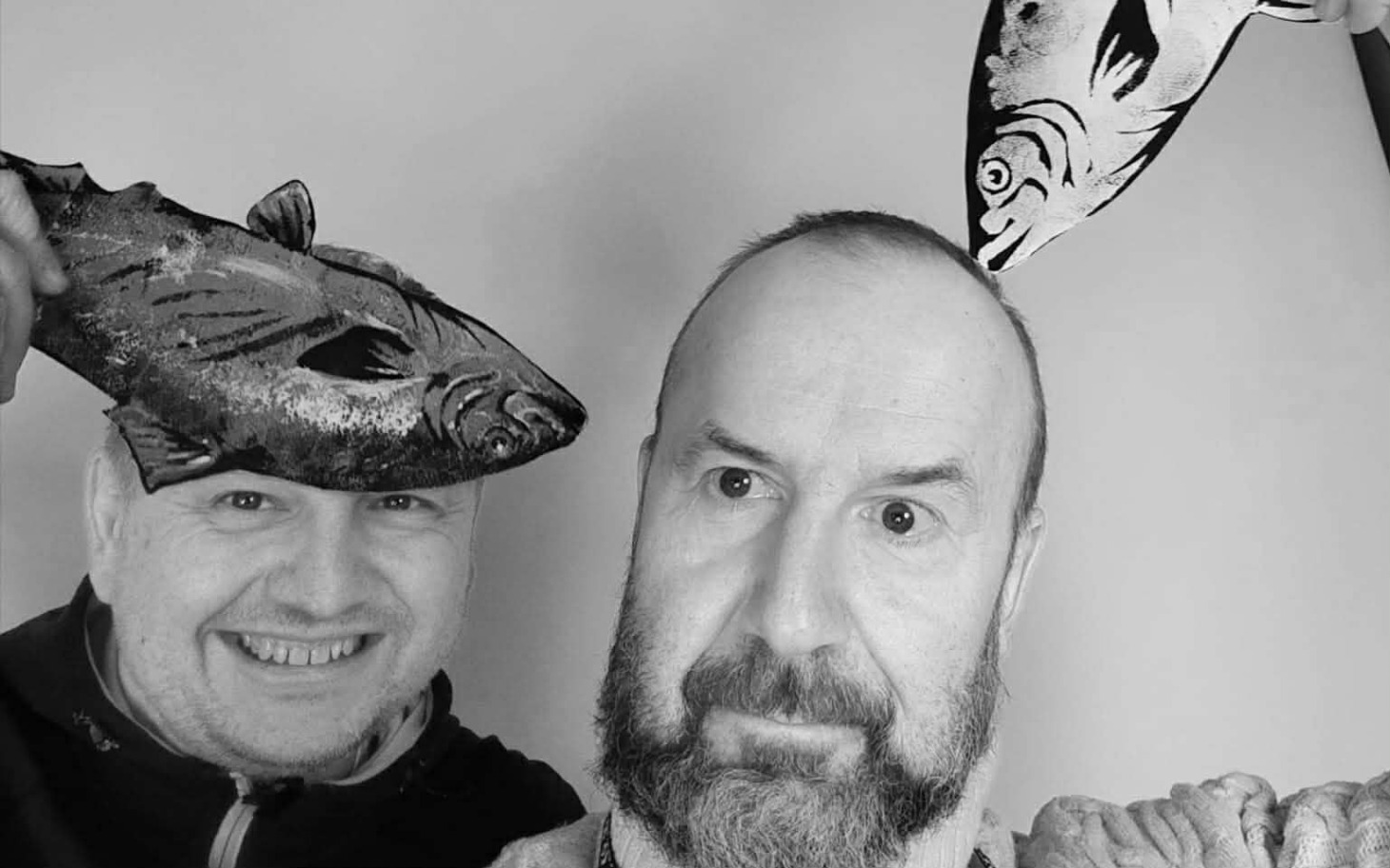 
        Dwaj mężczyźni pozujący z rybami na głowach w zabawnej scenerii.
    