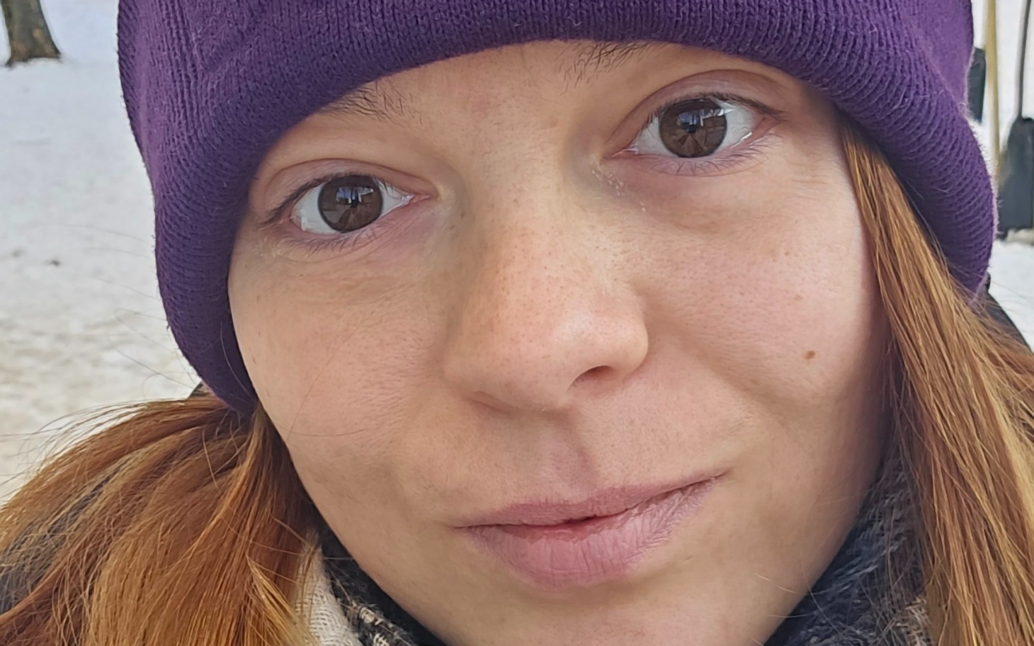 
        Portret kobiety w zimowej czapce na tle śniegu.
    