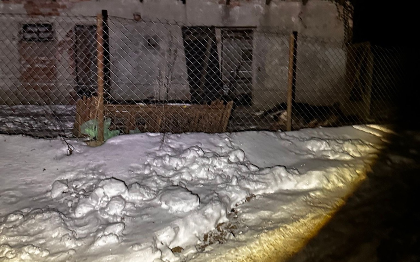 
        Opuszczony budynek otoczony śniegiem, z zamkniętymi drzwiami.
    