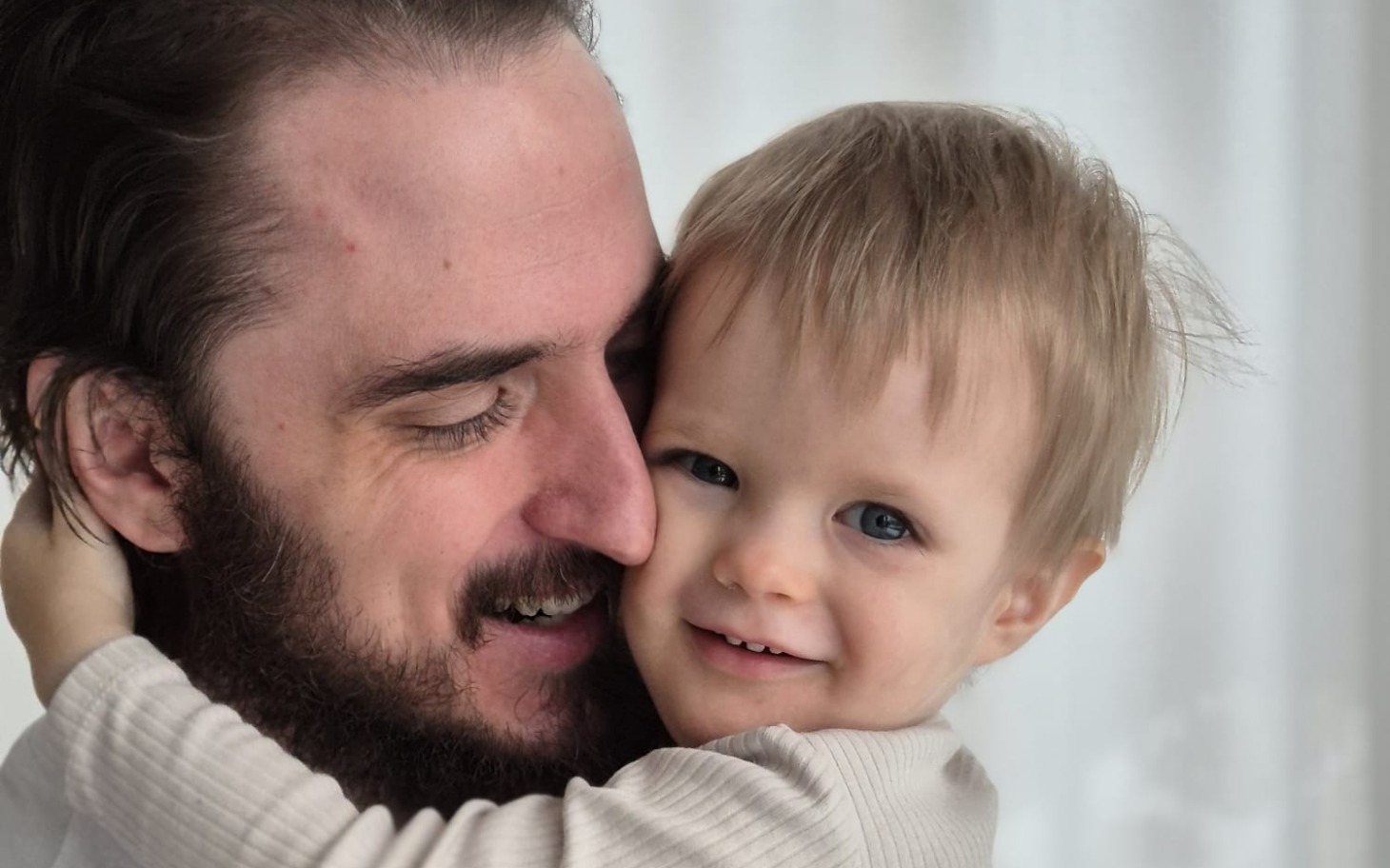 
        Uśmiechnięty tata przytulający swojego małego synka.
    