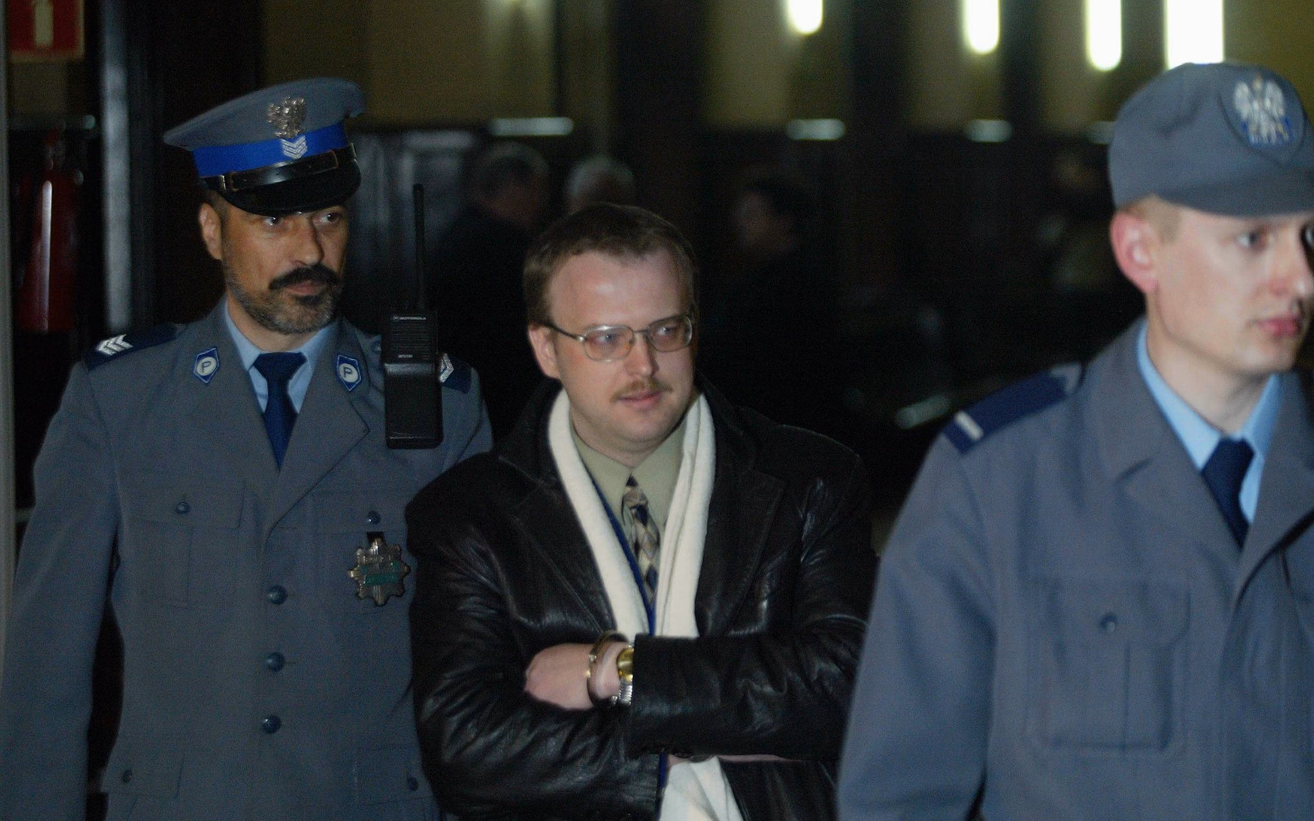 
        Mężczyzna eskortowany przez policję w sądzie.
    