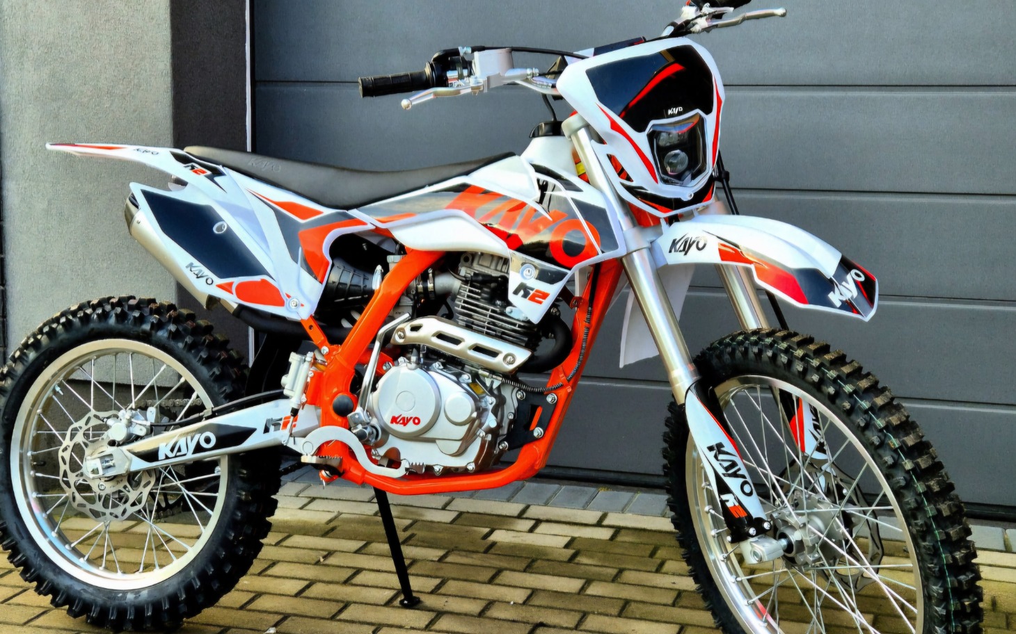 
        Motocykl terenowy w kolorach białym i pomarańczowym.
    