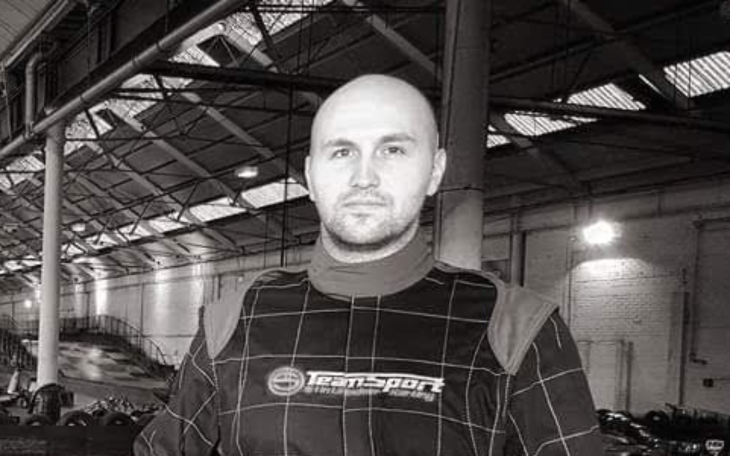 
        Mężczyzna w kombinezonie wyścigowym na torze.
    