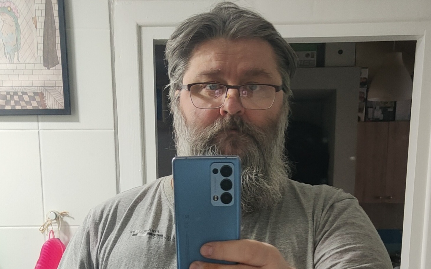 
        Mężczyzna z brodą trzymający telefon w lustrze.
    