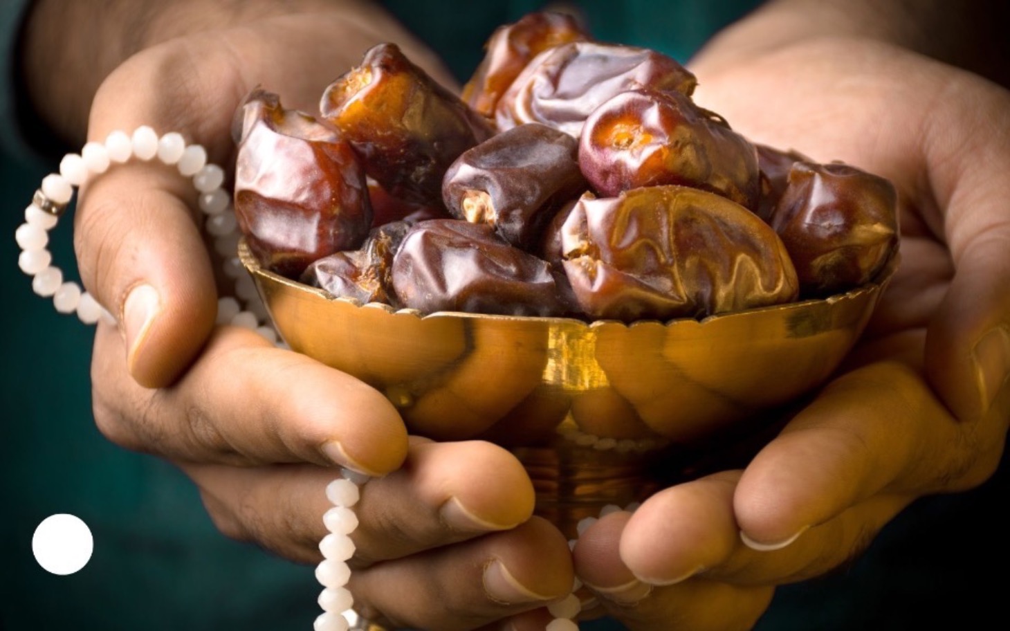 
        Ręce trzymające misę z daktylami, symbolizujące gościnność.
    