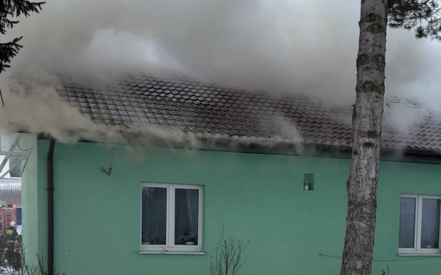 
        Dom w płomieniach, dym wydobywa się z dachu.
    