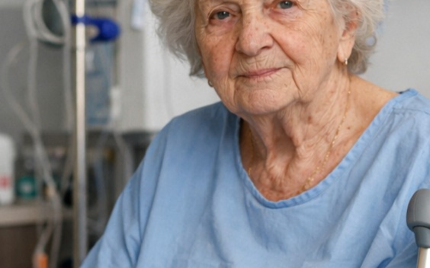 
        Starsza kobieta w szpitalu, uśmiechająca się do kamery.
    