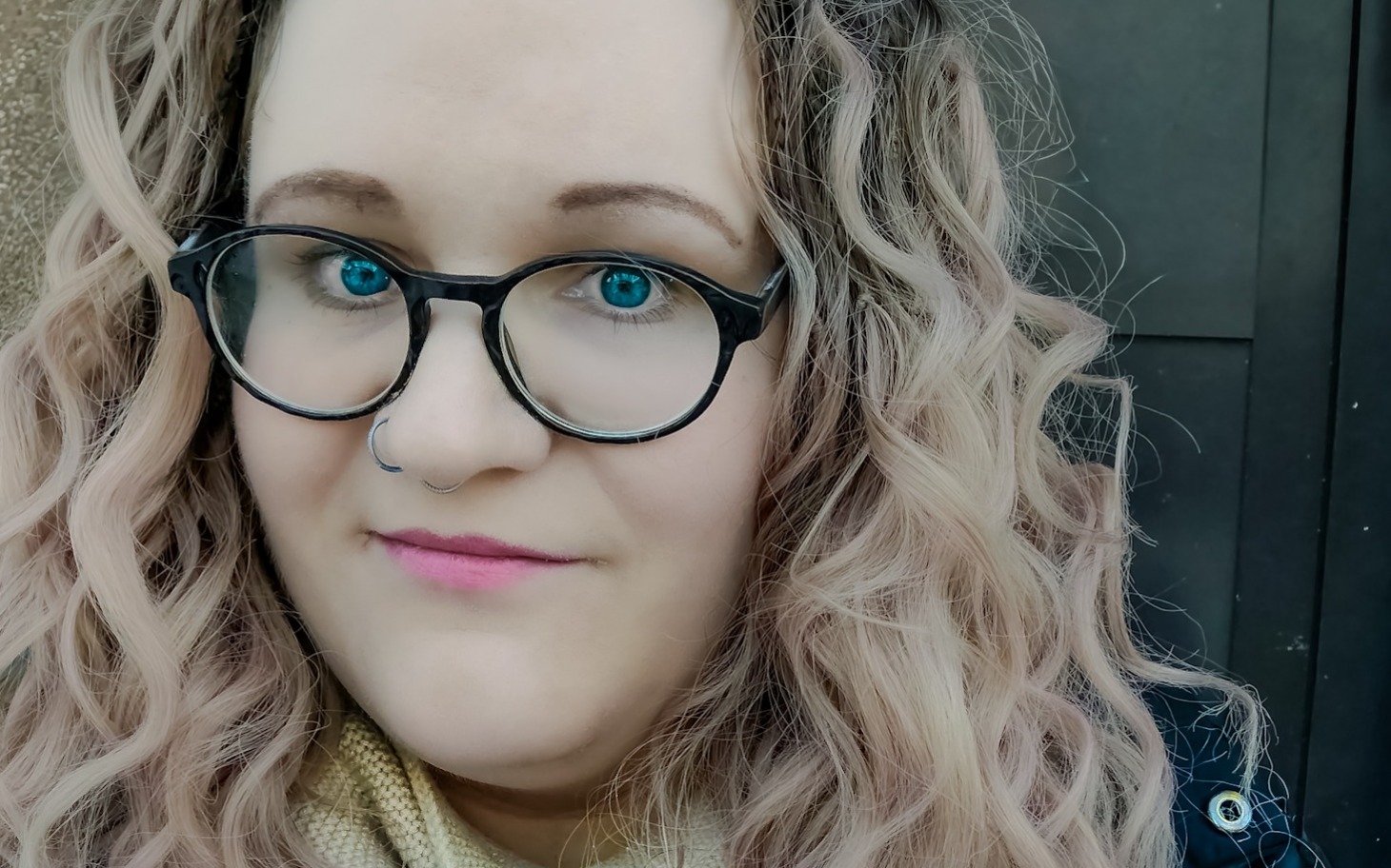 
        Kobieta z kręconymi włosami i okularami.
    