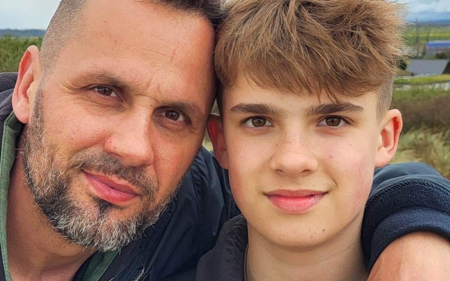 
        Mężczyzna z nastolatkiem, uśmiechają się do kamery.
    