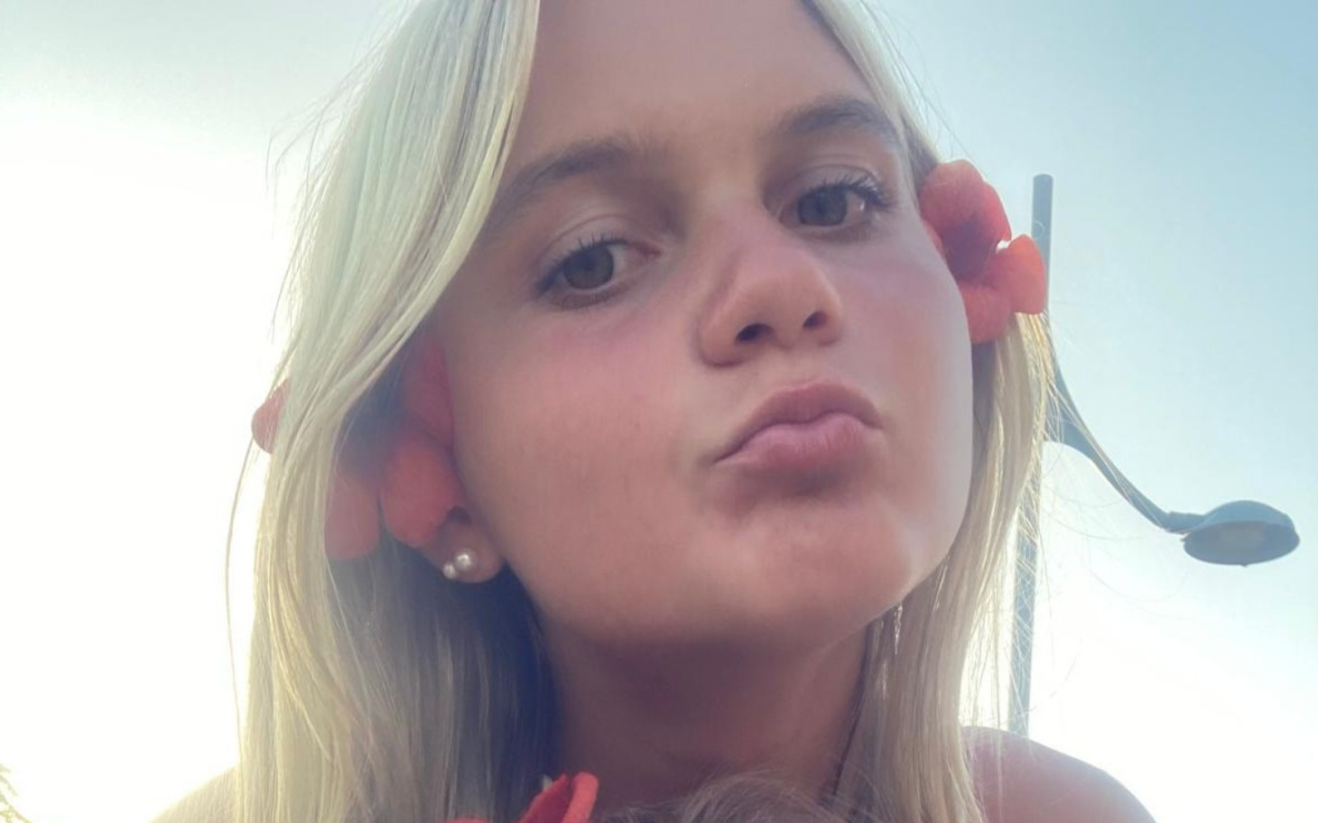 
        Młoda dziewczyna z kwiatami we włosach, uśmiechająca się do kamery.
    