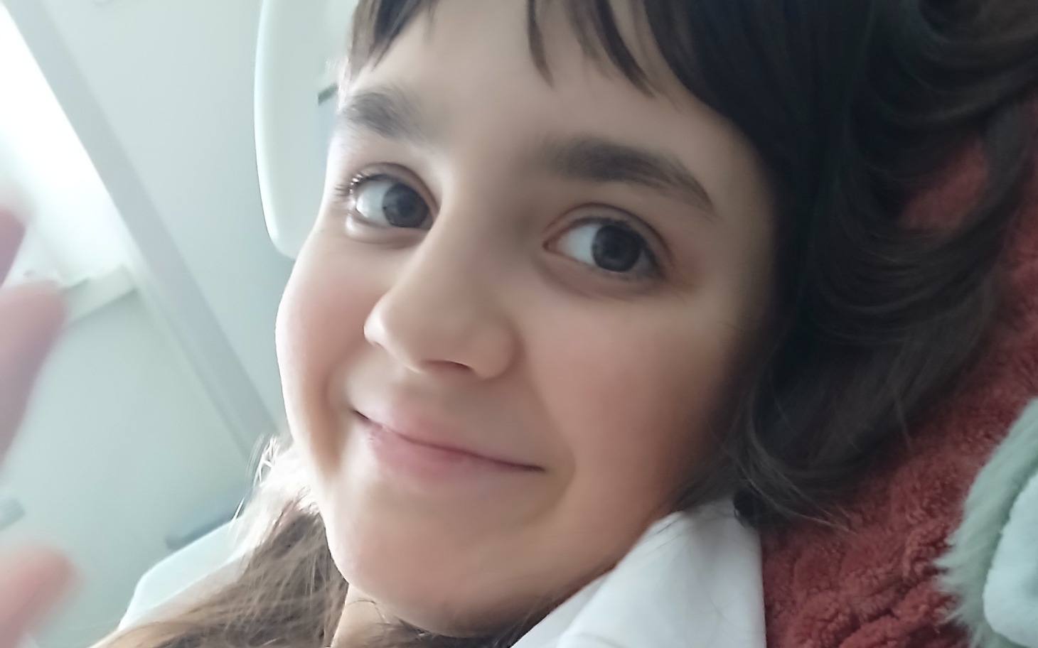 
        Uśmiechnięta dziewczynka leżąca na łóżku w szpitalu.
    