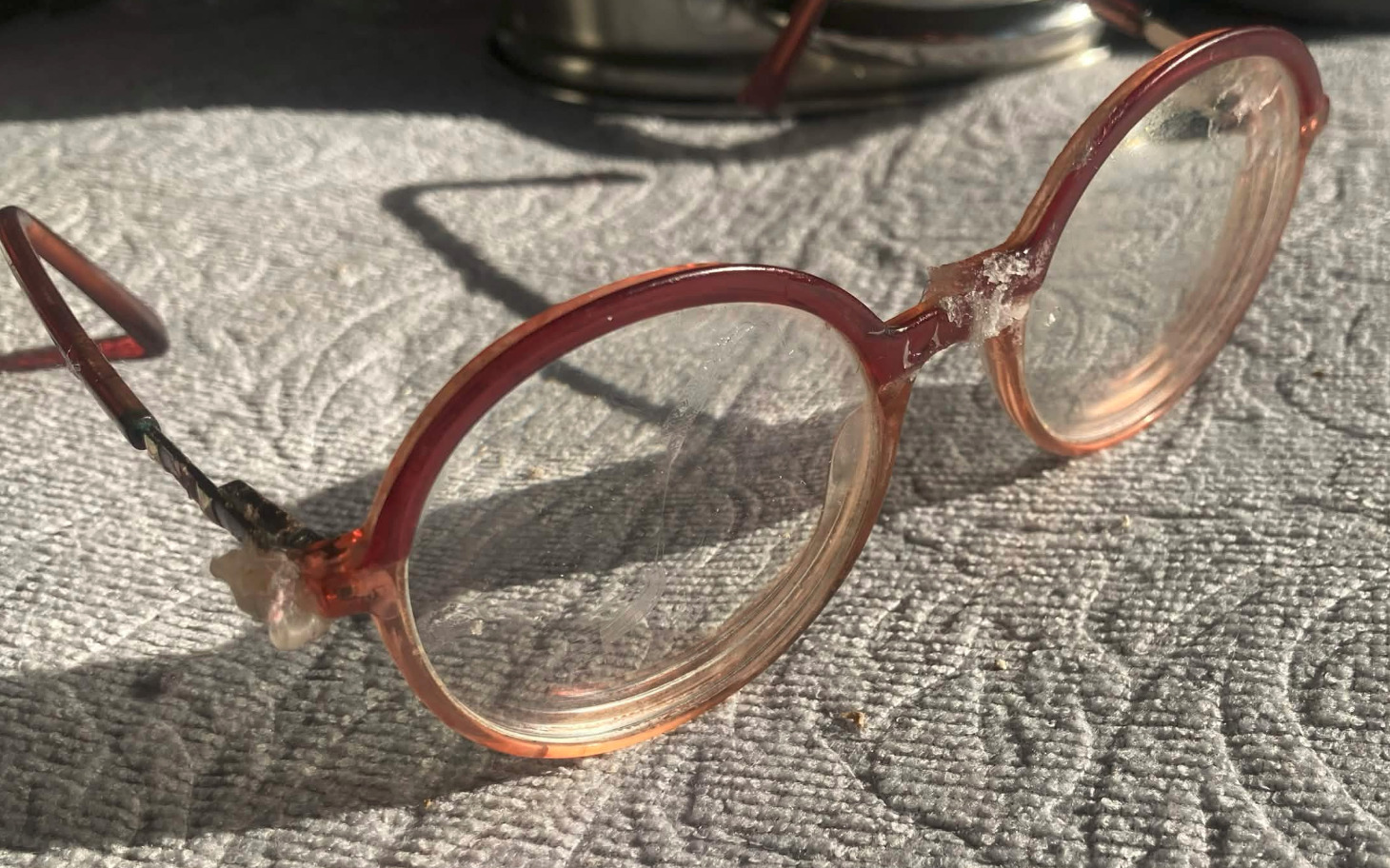 
        Okulary w różowej oprawie, zniszczone i brudne.
    